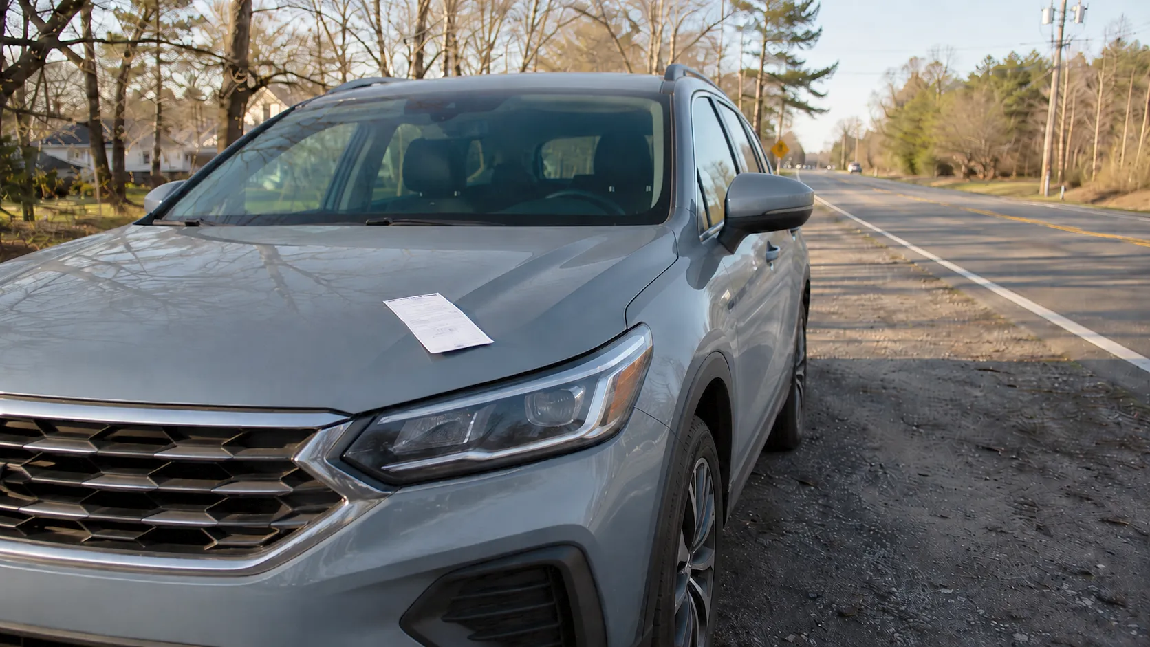 Paper speeding citation on the hood of a parked sedan after a roadside stop