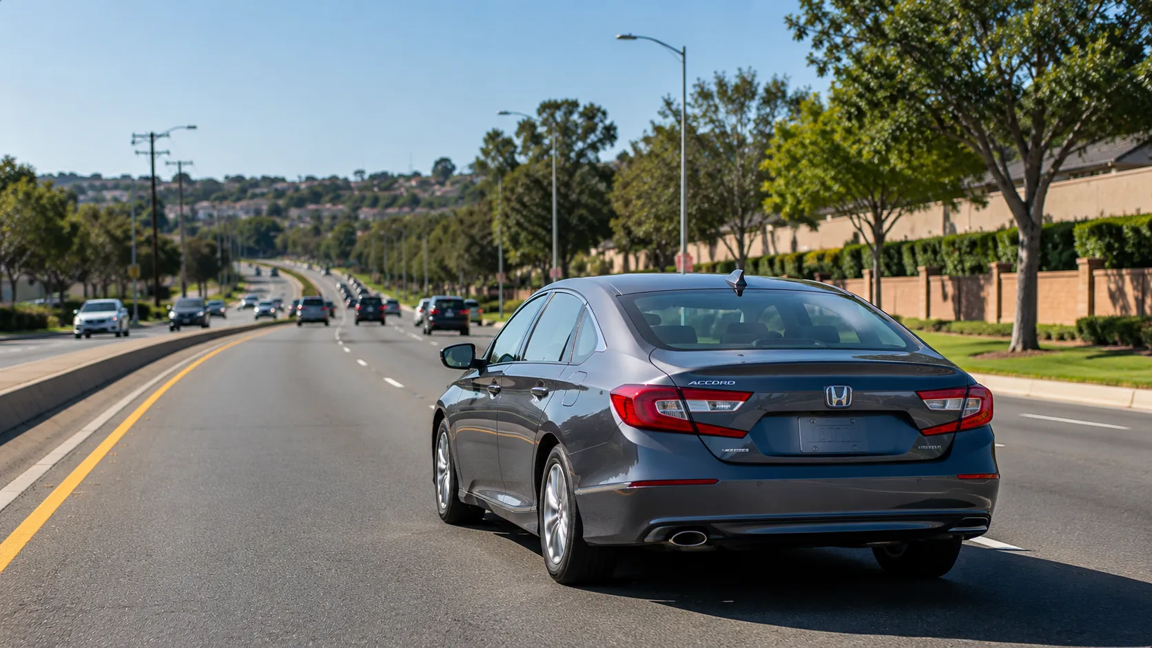 A gray sedan driving on a suburban multi-lane road, representing how traffic violations can affect car insurance rates.