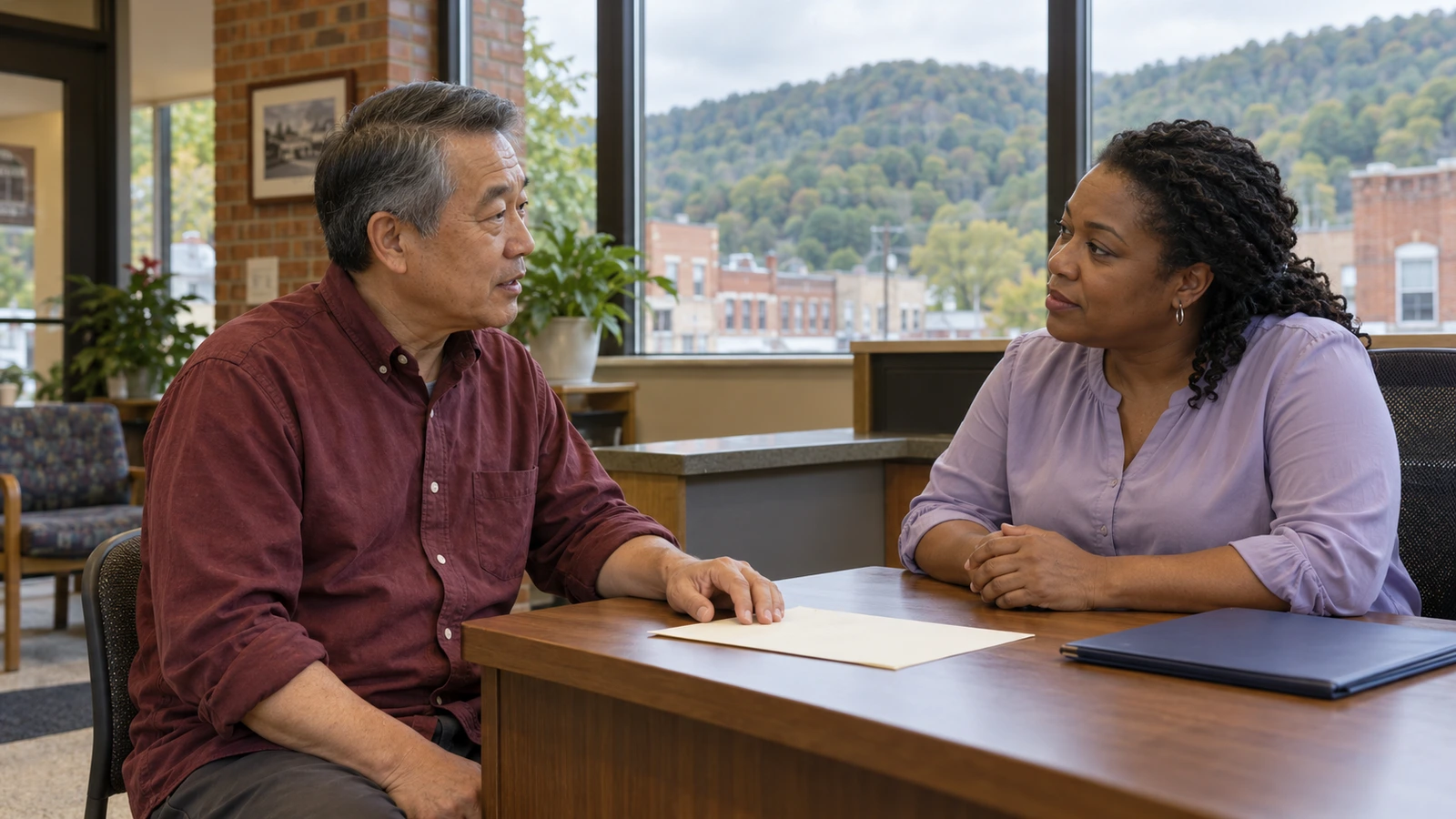 Man discussing course information with a woman at a community-center desk.